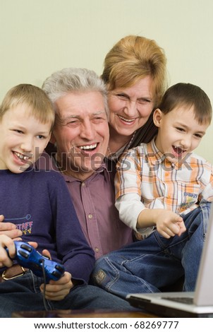 happy grandparents with their grandchildren play on the computer