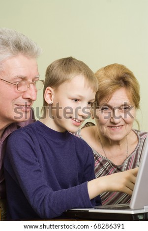 happy grandparents with boy play on the computer