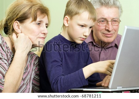 happy grandparents with boy play on the computer