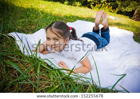 Pretty little girl lies on blanket in the park