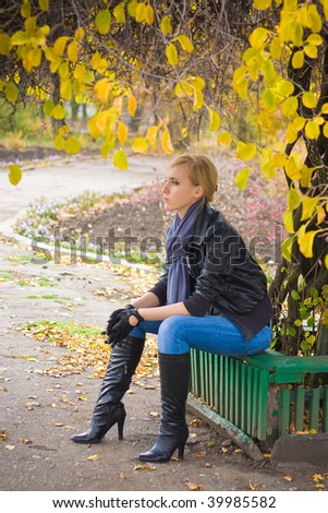 Sad young woman sit near autumn tree