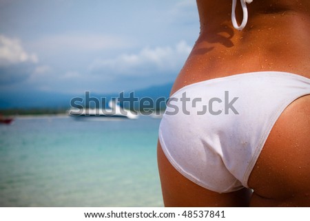A beautiful womans body on the beach with the boat view