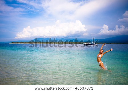 woman dancing on a tropical beach in the caribbean with the boat view