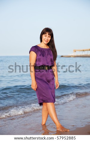 beautiful woman in a violet dress stand on seacoast