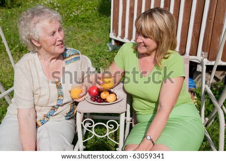 elderly woman has breakfast with her daughter in the garden