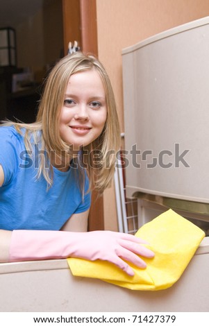 girl in blue shirt washes refrigerator