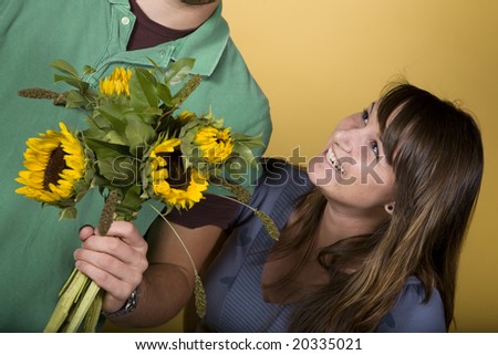 Girl laughing at man holding a bouquet of sunflowers