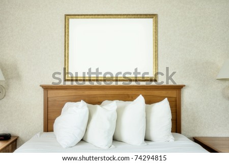 An empty frame hangs on the wall over a bed.