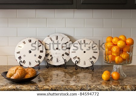Vintage clocks on a counter with oranges and croissants