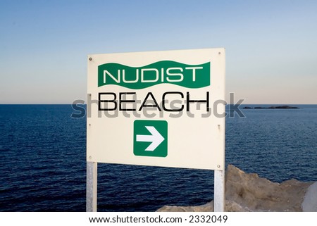 A sign indicating the direction of a nudist beach with the Adriatic Sea in the backgroung