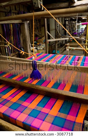 An old-style loom producing a colorful cloth