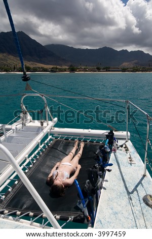 A young teenager sunbathing on the bow of a catamaran