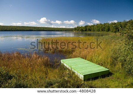A green wooden pier next to a lake in central Quebec.