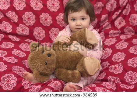Little girl in her pyjamas cuddling her teddybear.