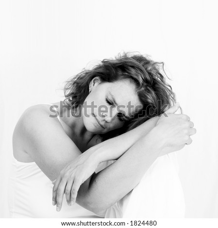Black/white photo of a woman resting her head on her knee. High key.