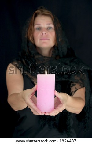 Graceful woman holding up a lit candle.