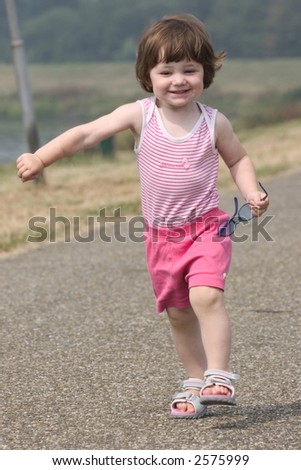 Little girl running with a big smile on her face.