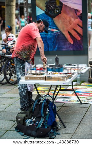 STUTTGART, GERMANY - June 15, 2013: An artist is action painting in Koenigstrasse, the pedestrian area, on June 15,2013 in Stuttgart, Germany.Due to the late summer, downtown Stuttgart is pretty busy