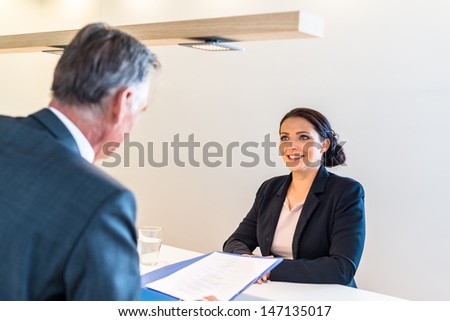 Recruiter (middle aged business man) checking the candidate, an attractive younger woman,  during job interview