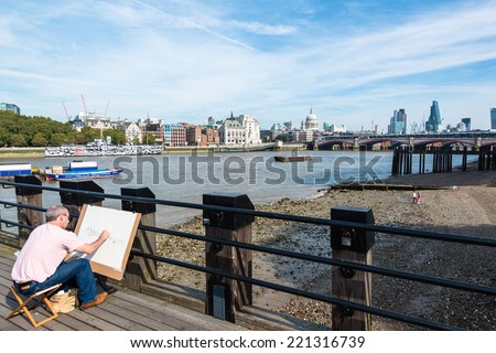 LONDON, UK - SEPTEMBER 28, 2014: An artist on the South Bank of river Thames is painting the skyline from Saint Pauls Cathedral up to the modern finance district on September 28, 2014 in London, UK.
