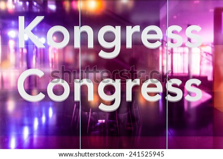 Congress room: Glass wall with German and English wording for congress with seats in the background