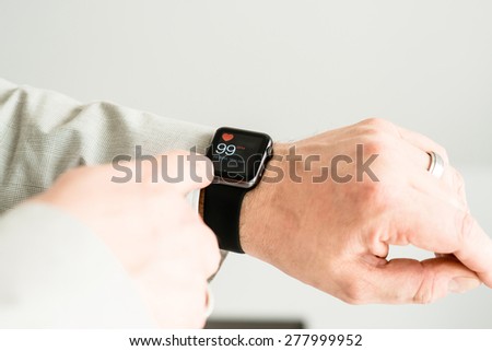 OSTFILDERN, GERMANY - MAY 14, 2015: A businessman is checking his pulse using his black Apple Watch Sport. The Apple Watch is the latest device by computer and smartphone manufacturer Apple Computer