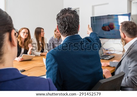 Discussion during a business meeting in a conference room - mixed caucasian team rather casual, ambiente might suggest a startup or an agency