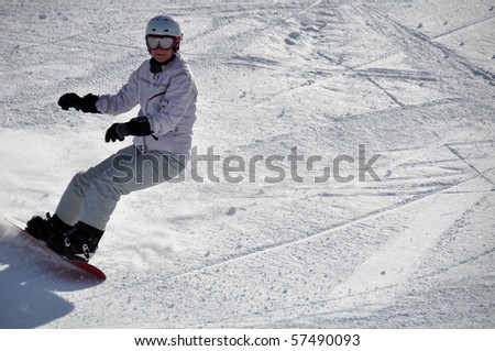Middle aged female snowboarder wearing helmet and snow goggles in powder snow on steep hill - shot in Livigno, Italian Alps