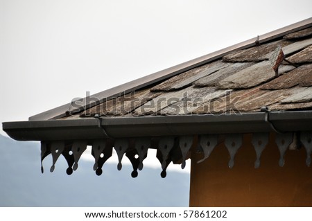 Detail of old stone roof with richly decorated rain pipe