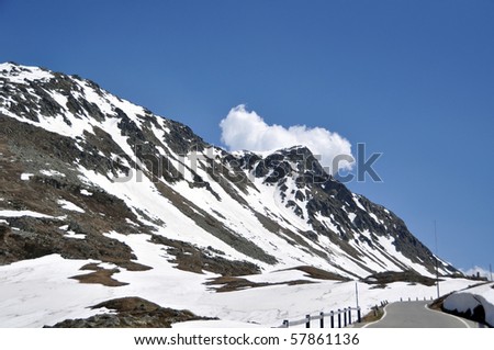 Mountain pass road through snow covered rocks on Spluegen Pass in Switzerland, Europe