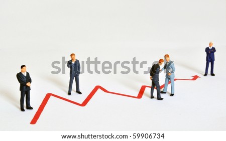 Group of managers (model railroad figures) positioned around graph showing rising business development.