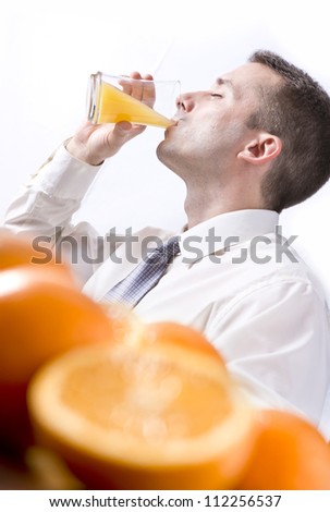 Oranges on table, man drinking orange juice