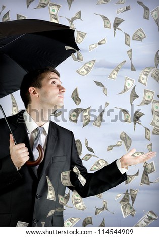 Business man holding an umbrella, money falling from the sky
