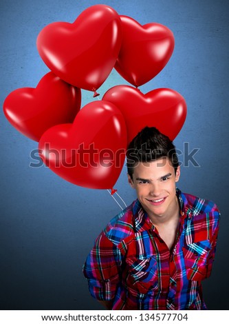 Young man holding heart shaped balloons behind his back