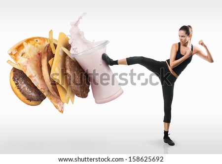 Fit young woman fighting off fast food - stock photo