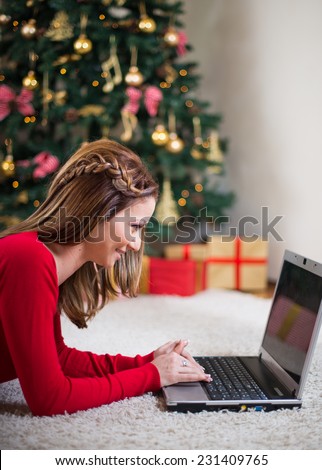Young woman using a laptop in front of Christmas tree