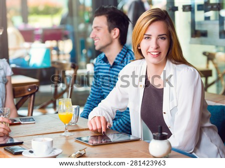 Young woman sitting at a table with her friends in a cafe