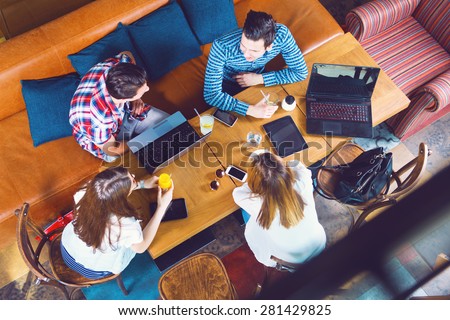 Group of young people sitting at a cafe, talking and enjoying, top view