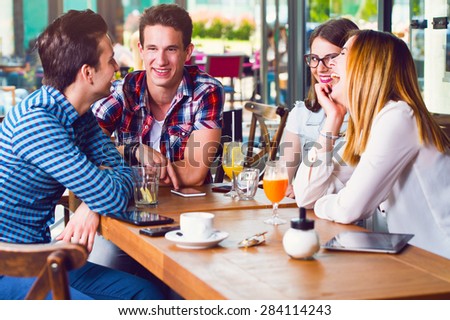 Group of young people sitting at a cafe, talking and enjoying