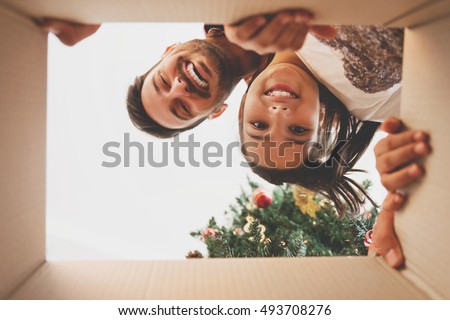 Father and daughter opening a Christmas present, view from inside of the box