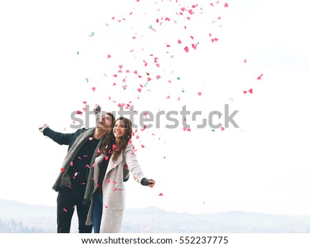 Cute young couple in love, outdoors with hearts falling