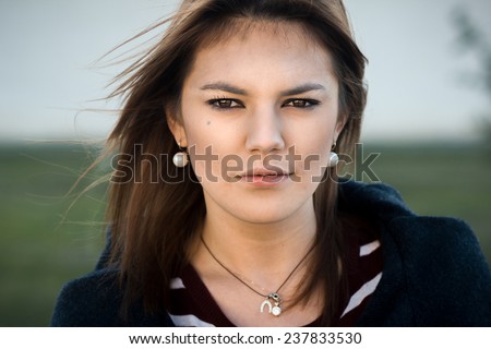 Outdoor portrait of young beautiful woman with stern look