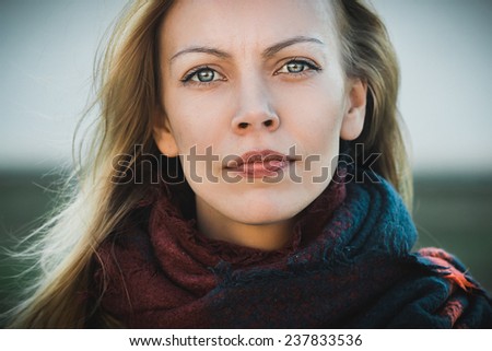 Outdoor portrait of young beautiful blonde woman with stern protest look