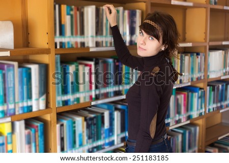 Female student searching for book in college library. Selective focus on face.