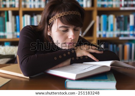 Tired student girl sleeps in college library on books. Resting student. Selective focus on face.