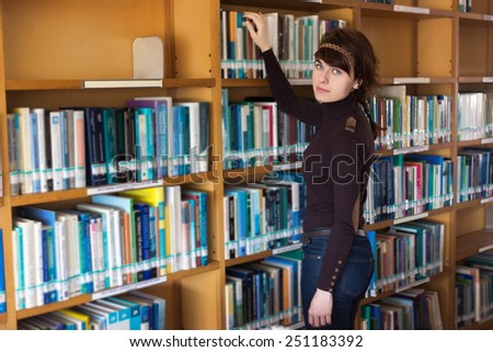 Female student searching for book in college library. Selective focus on face.