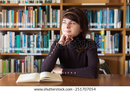 Beautiful student girl studying in college library. Thinking on ideas. Selective focus on face.