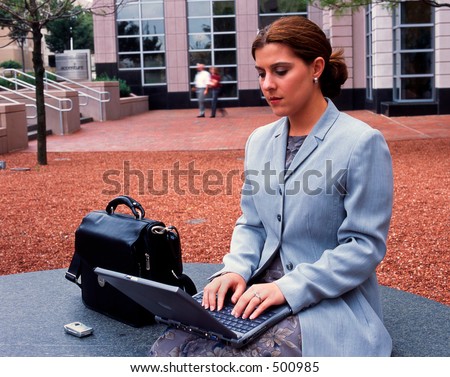 Business woman on laptop computer outside high rise