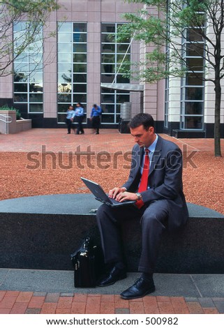 Business man on laptop computer outside high rise