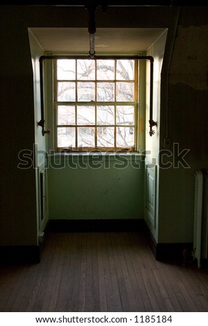 Abandoned room with wood floors only lit by the sun light coming through an old window.